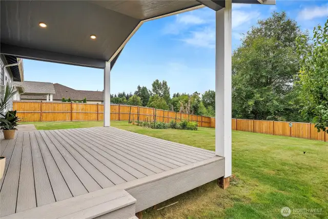 Covered back deck overlooking a fully fenced yard with garden space and a preserved greenbelt perfect for relaxing or entertaining year-round.