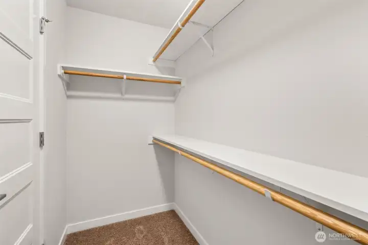 Primary walk-in closet with solid shelving.