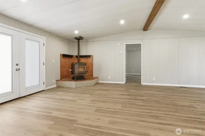 Family room with vaulted ceilings and new LVP flooring, french doors to the private back patio and courtyard, opens to the living room and kitchen