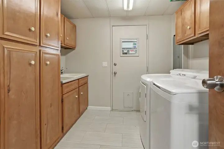 Utility room with full size washer and dryer include and a sink