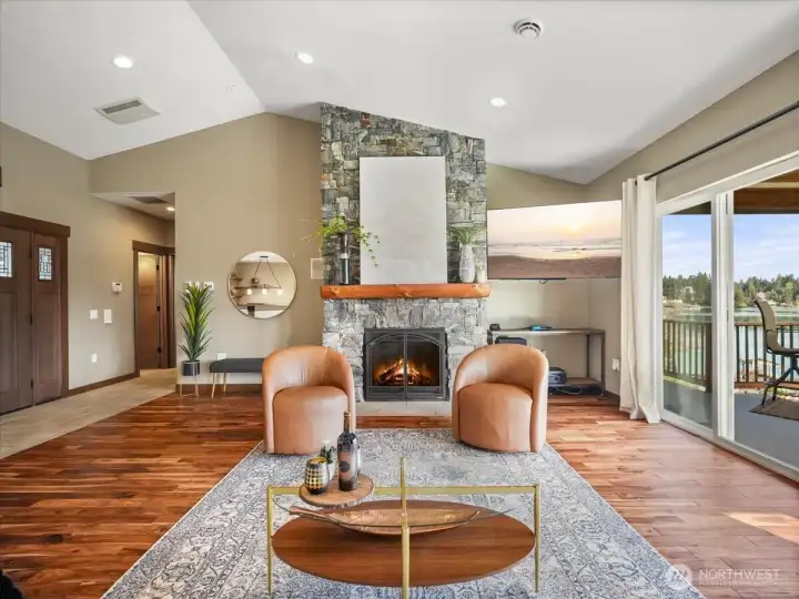 A striking floor-to-ceiling stacked stone gas fireplace anchors the living room, accented by a beautifully crafted wood mantel.