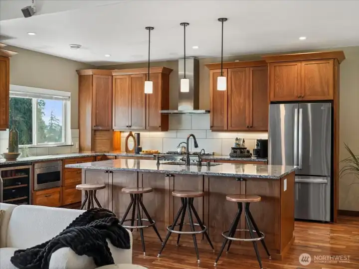 The kitchen is thoughtfully equipped with an undercounter microwave, a wine fridge, and convenient pull-out shelving in the  cabinet pantry for effortless organization.