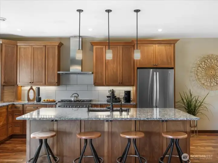 Beautifully designed kitchen showcases Huntwood soft-close cabinetry, elegant quartz countertops, a refined tile backsplash, and under-cabinet lighting that adds both warmth and function.