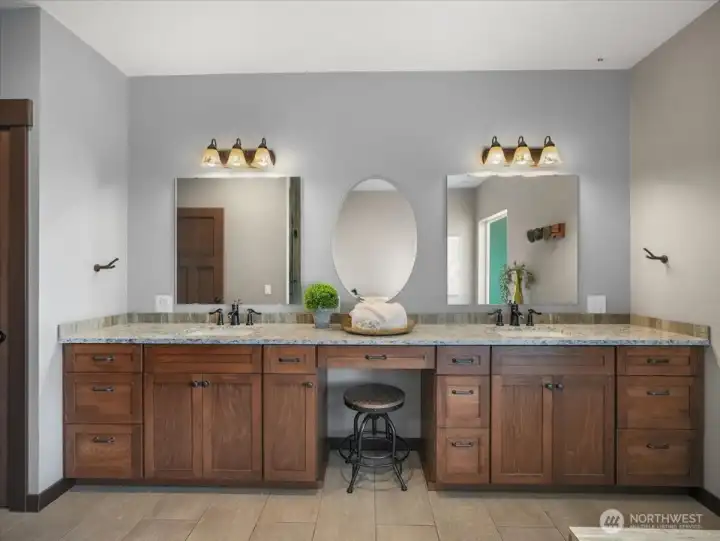 The primary bath features an expansive vanity with a dedicated seating area, perfect for a comfortable makeup or grooming space.