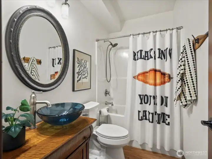 Downstairs full bath showcases a distinctive vessel sink set atop a beautifully restored 1890 vanity, adding timeless character and charm. This unique feature blends vintage elegance with modern functionality for a truly one-of-a-kind space.