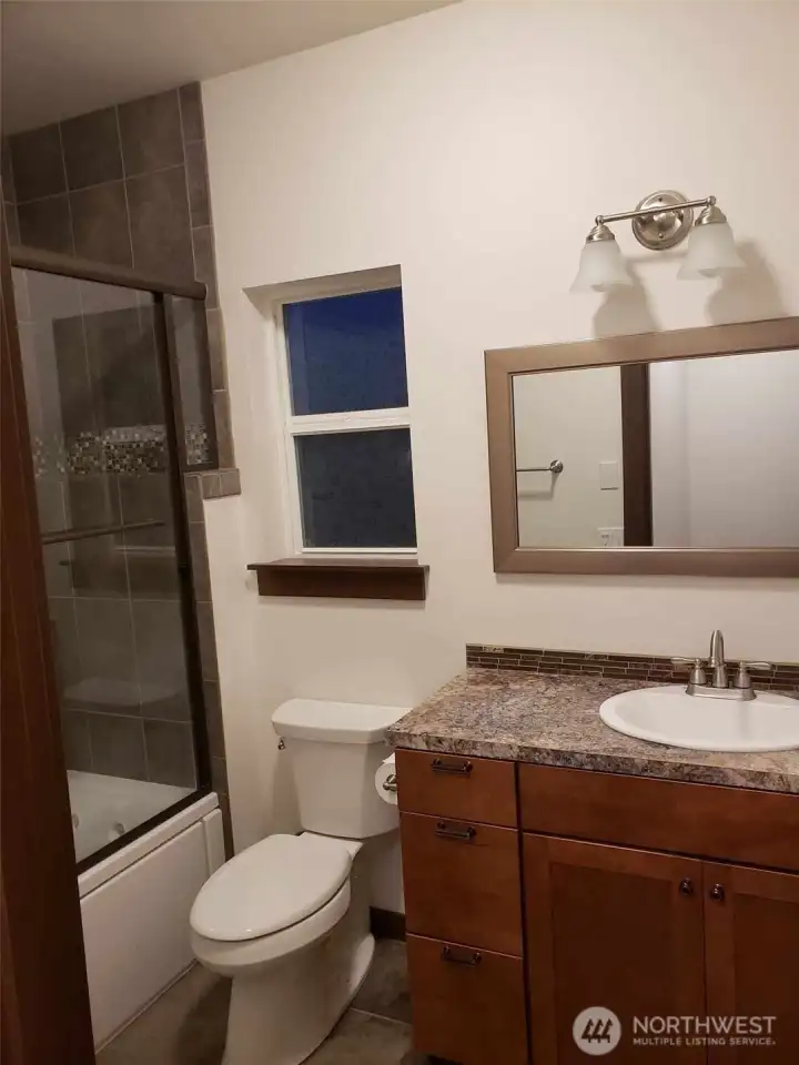 ADU has full bathroom with jetted tub, glass shower doors and granite countertop.