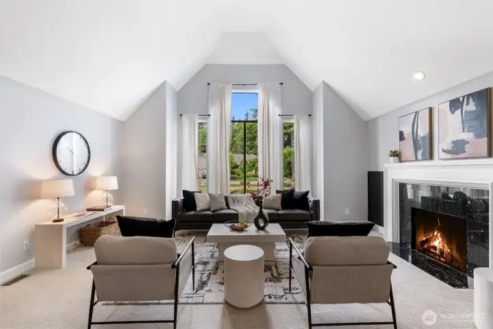 The front family room features soaring high ceilings and a cozy gas fireplace with nearly floor-to-ceiling windows overlooking the manicured front yard.