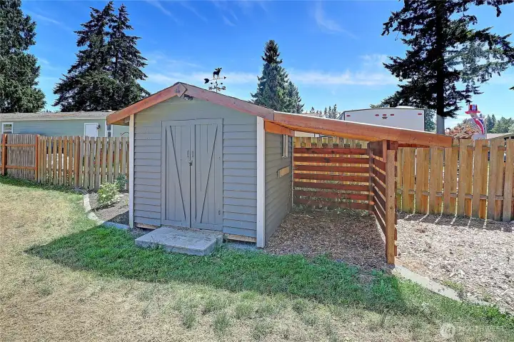 Storage shed with attached covered area for tools, equipment, or outdoor storage.