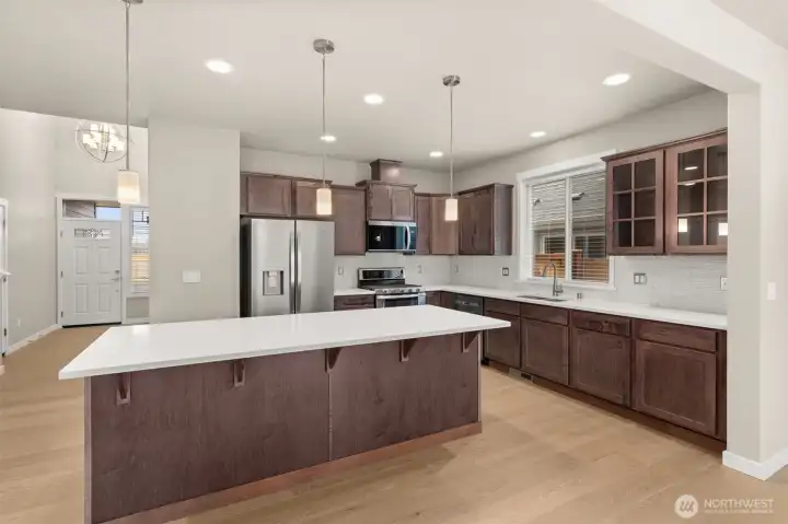 Kitchen features sable-stained Maple Cabinets and Quartz countertops with tile backsplash. Whirlpool stainless steel gas double oven is standard. This home also includes a refrigerator!