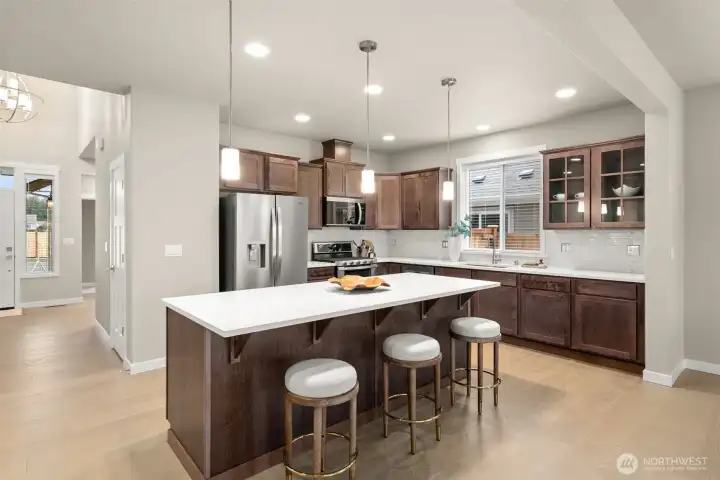 Kitchen features sable-stained Maple Cabinets and Quartz countertops with tile backsplash. Whirlpool stainless steel gas double oven is standard. This home also includes a refrigerator!