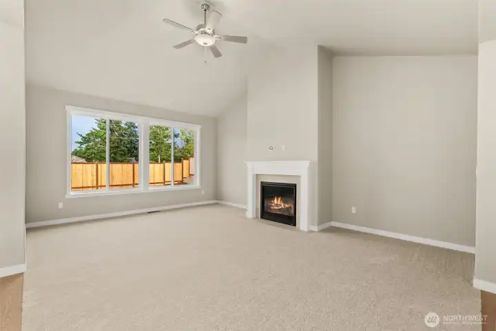 Living room with plenty of natural light featuring cozy gas fireplace with tile surround and ceiling fan.