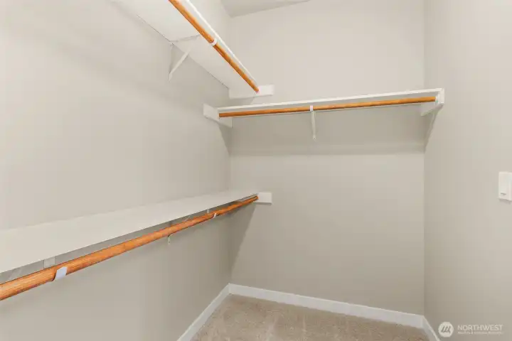 Primary walk-in closet boasts of hanging space and solid wood shelving.