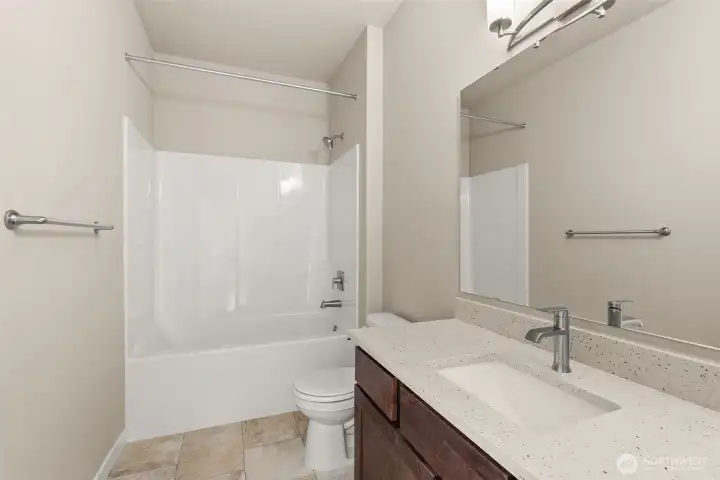 Full bathroom with undermount sink in Sable-stained Maple cabinet, quartz countertop with backsplash and tub/shower.