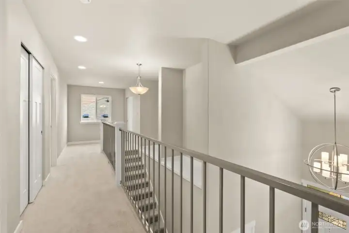 Bright and open upstairs hallway featuring modern metal railing with a view overlooking the main level.
