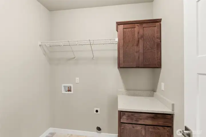 Separate laundry room with cabinets and a high hanging shelf for extended storage.