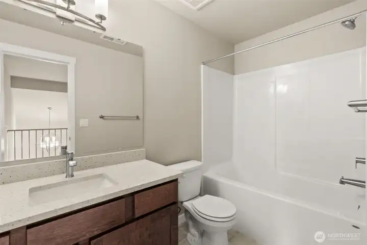 Crisp and clean 3rd bathroom located in second level with quartz countertop, maple wood cabinetry in sable-stain, and a shower tub combo.