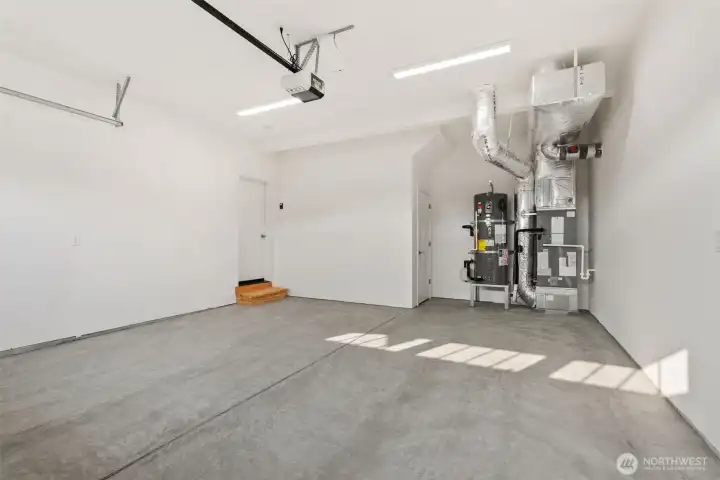 Spacious 2 car garage with extra storage. This photo also showcases HVAC system, water heater and clean concreate flooring.