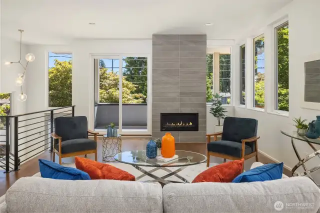 Great room with walkout covered deck, windows framing the space, and fire place (fire added for looks, buyer to verify functionality).
