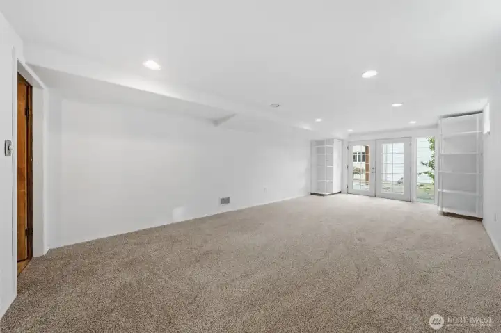 Large family room with carpet and French doors leading to patio.