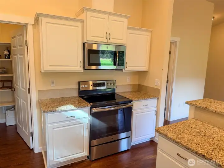 Plenty of cabinetry and counter space around the microwave, stove, and oven facilitates cooking in this functional kitchen.