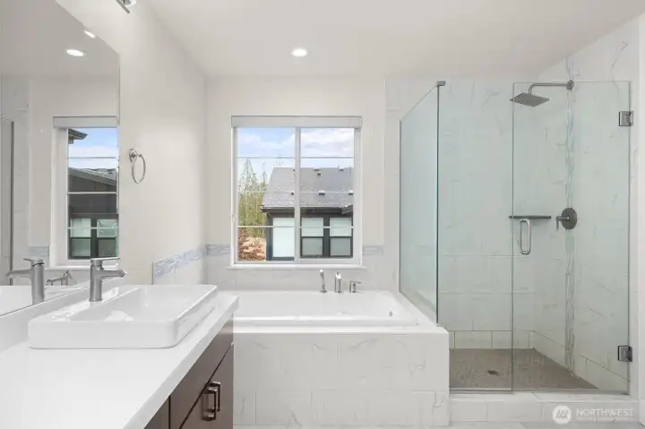 The primary bathroom feels like a private retreat, featuring a luxurious soaking tub and a spacious standalone shower.