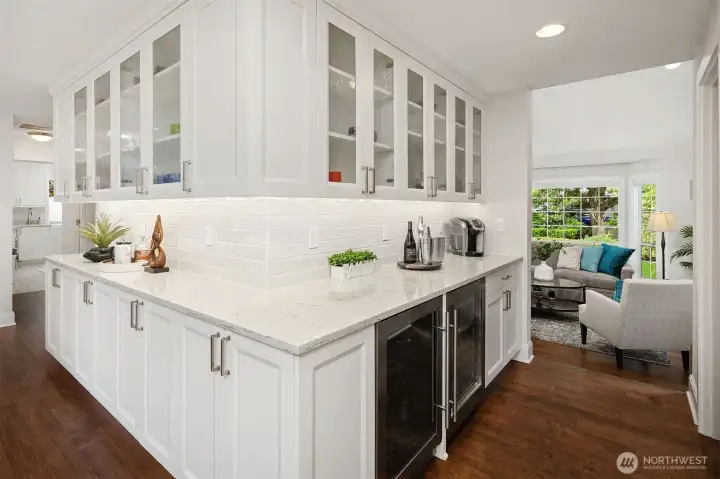 This is a photo of the beverage area and butlers pantry area with custom cabinets with display shelving above.  There are 2 beverage refrigerators below the counter as well as storage.