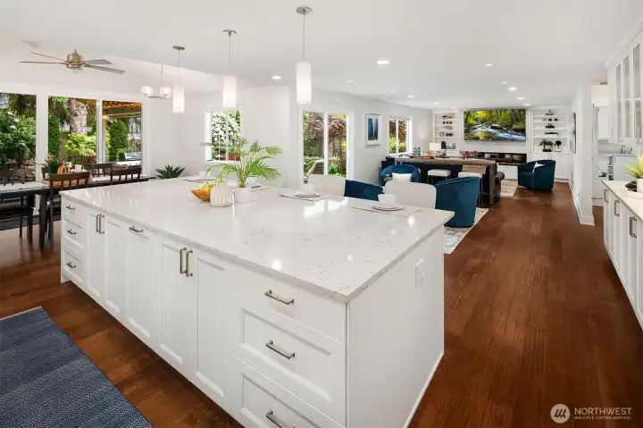 Looking from the kitchen island toward the sitting area and TV Room with 83" TV and custom shelves flanking either side.