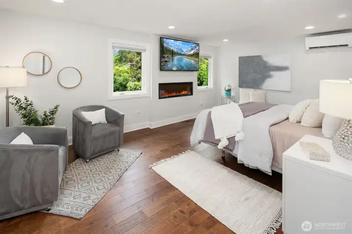 The primary bedroom with Hardwood floors, wood wrapped windows, Electric Fireplace with color change and heat settings.  Windows on either side of the TV area have top down/ bottom up black out blinds.  There is a seperate mini split that runs off the main Furnance/ heat pump to assure you are comfortable at nigh.