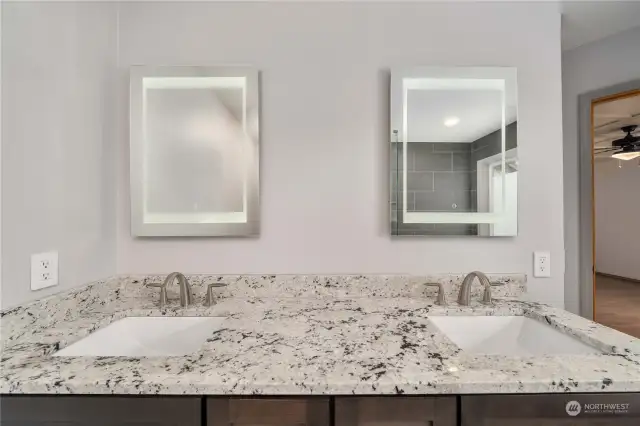 Granite countertops with new undermount double sinks, faucets and upscale mirrors with individual inside lighting.