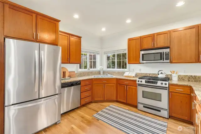 LIght-filled and spacious kitchen with stainless appliances, gas cooking, hardwood floors and a eating bar(peninsula) for a quick bite.