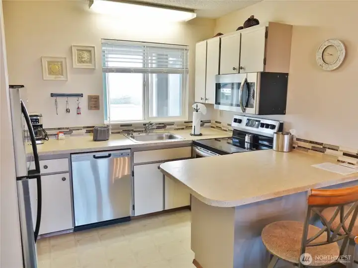 Fully-equipped Kitchen w/ Stainless Steel appliances, Eating Bar, and kitchenware.