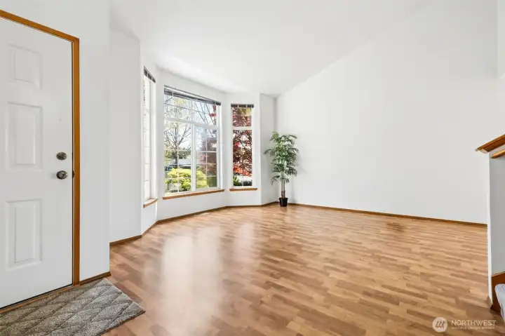 Bright and cheery living room with bay window and vaulted ceilings.
