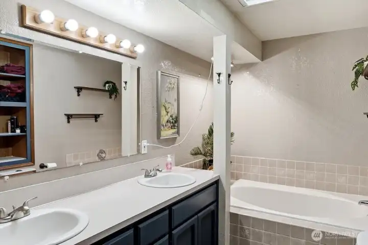 Five piece primary bathroom features a garden soaking tub and a walk in shower
