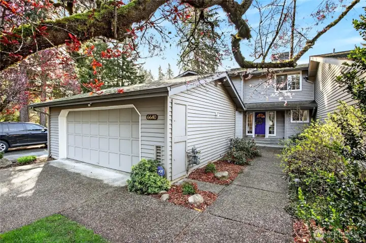 Charming townhome with 2-car garage, mature landscaping & blooming tree. Quiet setting with inviting entry, lush greenery & great curb appeal.