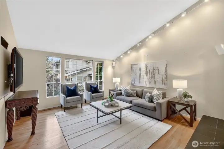 Bright living room with large windows, hardwood floors & stylish finishes. Spacious layout with cozy seating, modern lighting & great natural light. Gas firplace off to the right.