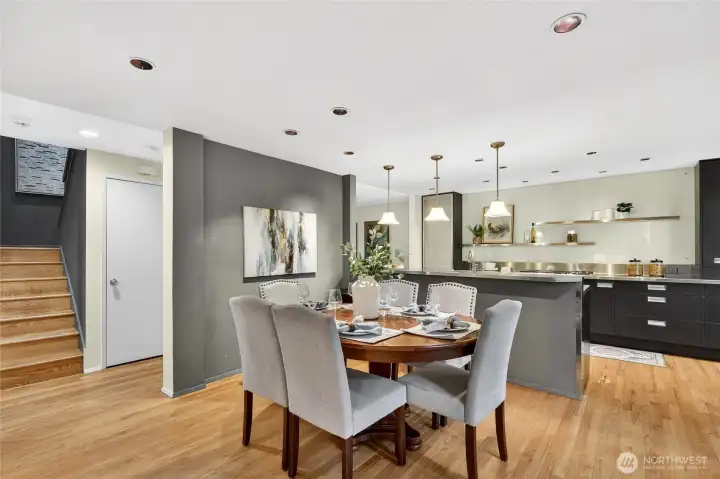 Spacious dining area with hardwood floors & modern lighting flows into updated kitchen with sleek cabinetry, island seating & clean contemporary finishes.