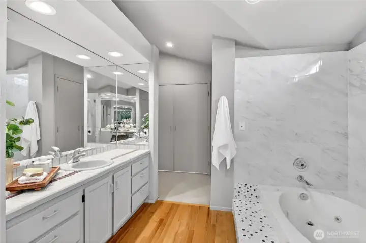 Spacious primary bath with dual vanity, expansive mirrors & abundant storage. Jetted soaking tub with elegant tile surround creates a bright, spa-like retreat.