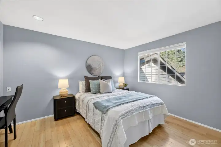 Bright & inviting second bedroom with hardwood floors, soft neutral tones & abundant natural light. Well-proportioned layout offers flexibility for guests, home office or everyday comfort.