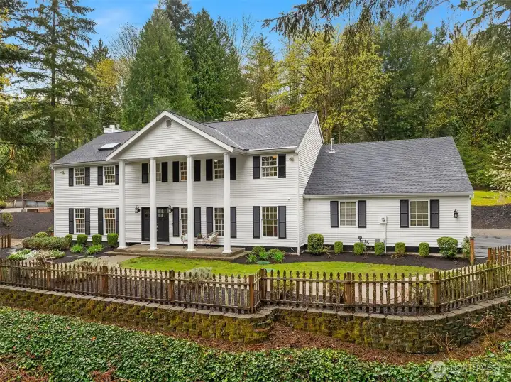 This is the address people mean when they talk about what makes Woodinville special — a nearly acre colonial estate tucked privately into the trees on Hollywood Hill, minutes from world-class tasting rooms, trails, dining, and everything the area is becoming.