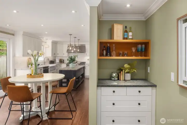 Built-in bar nook with open shelving and stone countertop sits just off the casual dining area and kitchen — the perfect setup for hosting without missing the conversation