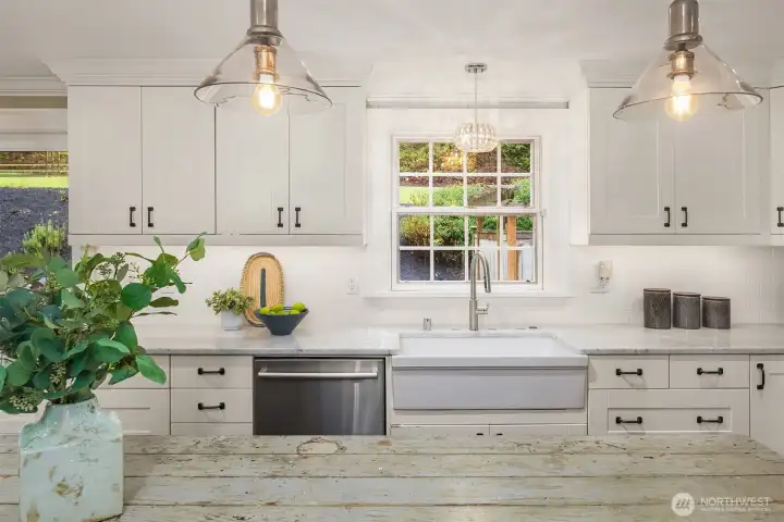 Gourmet kitchen with slab marble countertops, farmhouse sink, subway tile backsplash, white shaker cabinetry, and pendant lighting