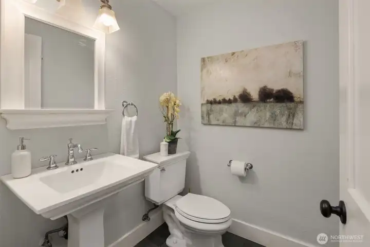 Charming powder room with pedestal sink, chrome fixtures, and classic tile flooring