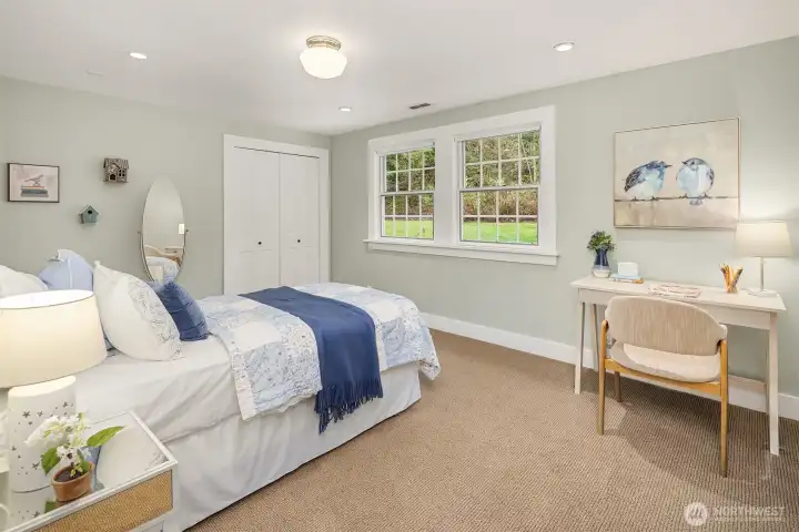 Light-filled bedroom with dual windows framing lush garden views and soft carpet — a serene and restful space