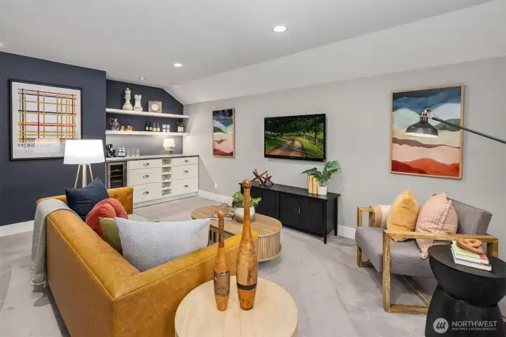 Bonus room with wet bar, beverage fridge, built-in shelving, media wall, and generous flexible living space