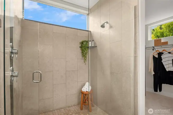 This spacious shower boasts a high transom window for natural light as well as a rain shower mounted in the ceiling.