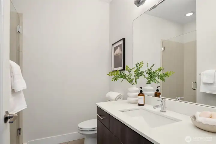 This second bathroom (four total) is just around the corner from the second bedroom and features an undermount sink and tiled shower and floor.