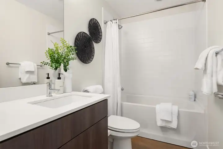 The lower full bath has a large vanity with undermount sink and a tiled bathtub.