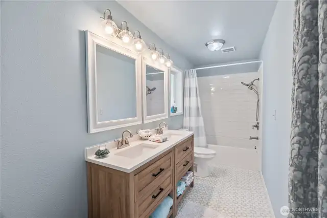 Primary Ensuite bath with double sinks, tile flooring & shower surround