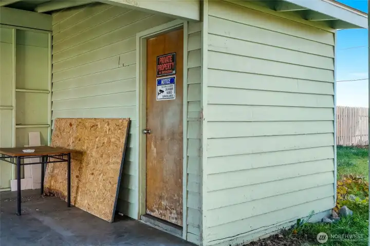 Storage room at the back of the carport, with shelving.