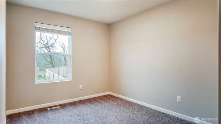 Comfortable secondary bedroom with window overlooking backyard.